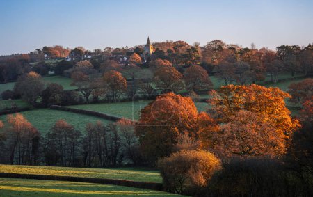 Téléchargez les photos : Autumn dawn sunlight on St Giles church and surrounding woodland countryside in Dallington east Sussex south east England Royaume-Uni - en image libre de droit