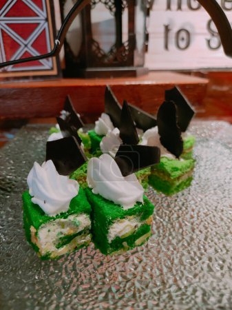 The green pandan sponge cake served on a glass plate, complete with attractive toppings, is very appetizing.