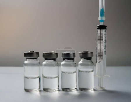 Eine medizinische Spritze, ausgerichtet mit einem transparenten Fläschchen auf weißem Hintergrund, symbolisiert die Impfung