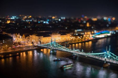 Budapest, Hungary - February 7, 2024: Landscape view of night Budapest from Citadella observation deck. Focus tilted to Fovam Ter street. Liberty bridge and Central Market on the middleground.