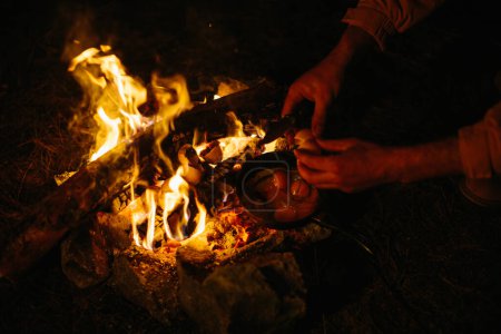 Photo for A traveler cooks fried eggs on a bonfire. The concept of travel and survival in the wild. - Royalty Free Image
