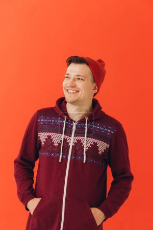 Téléchargez les photos : Jeune homme en pull de Noël et chapeau sur fond de couleur - en image libre de droit