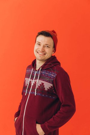 Téléchargez les photos : Un jeune homme dans un kigurumi de Noël et un chapeau tricoté sur un fond coloré - en image libre de droit