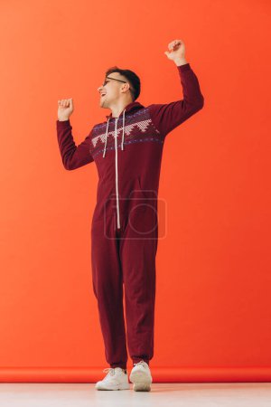 Photo for A young man in sunglasses and a Christmas kigurumi dances on a red background. - Royalty Free Image