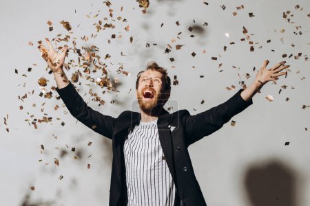 Photo for Concept of celebration and victory. Stylish young man isolated on white background under glittering confetti. - Royalty Free Image