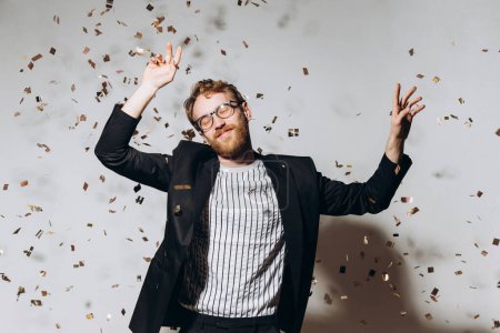 Photo for Celebration time. Portrait of a happy guy dancing under glittering confetti. - Royalty Free Image