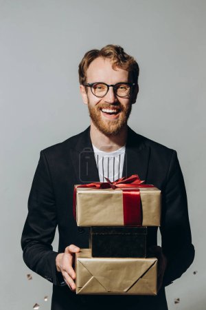 Foto de Hora de la celebración. Retrato de un tipo feliz sosteniendo una pila de cajas de regalo aisladas sobre fondo blanco en el estudio. - Imagen libre de derechos