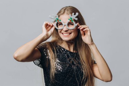 Photo for A young smiling blonde woman in glasses with deer antlers isolated on white background. Christmas and New Year concept. - Royalty Free Image