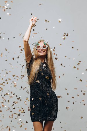 Foto de Una hermosa chica rubia está bailando bajo confeti reluciente. concepto de fiesta de Año Nuevo. - Imagen libre de derechos