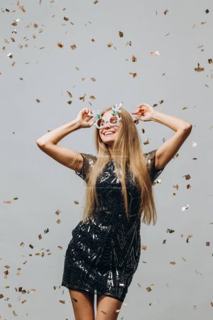 Téléchargez les photos : Une belle blonde danse sous des confettis scintillants. Concept de fête Nouvel An. - en image libre de droit