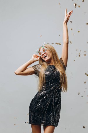 Foto de Una hermosa chica rubia está bailando bajo confeti reluciente. concepto de fiesta de Año Nuevo. - Imagen libre de derechos