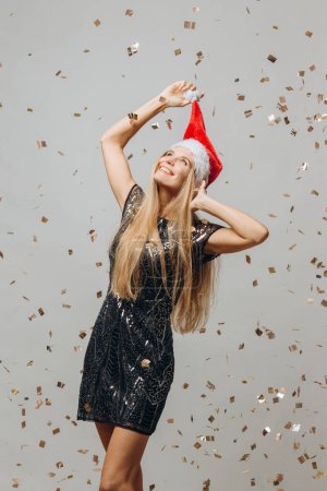 Foto de Hermosa rubia Santa niña bailando bajo confeti brillante. concepto de fiesta de Año Nuevo. - Imagen libre de derechos