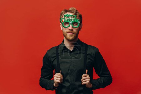 Téléchargez les photos : Charmant homme aux cheveux roux en lunettes de carnaval à la fête du Nouvel An. Studio photo. - en image libre de droit