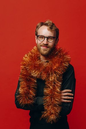 Photo for Red-haired cheerful man in glasses and golden boa at New Year party with confetti. Studio photo. - Royalty Free Image