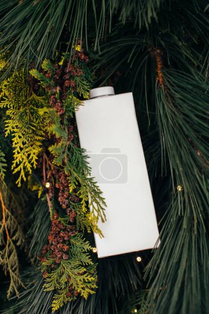 Foto de Una bolsa de papel de leche sobre un fondo navideño de ramas de pino. Mockup para el diseño del logotipo. - Imagen libre de derechos