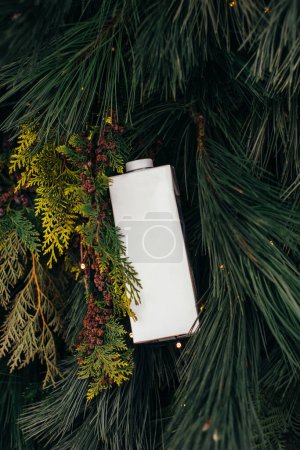 Téléchargez les photos : Un sac en papier de lait sur fond de Noël de branches de pin. Maquette pour la conception du logo. - en image libre de droit