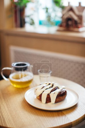 Téléchargez les photos : Gros plan de délicieux Cinnabon sur la table avec tasse de thé et théière. - en image libre de droit