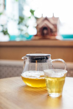 Téléchargez les photos : Gros plan de thé chaud dans une théière en verre sur une table dans un café. - en image libre de droit