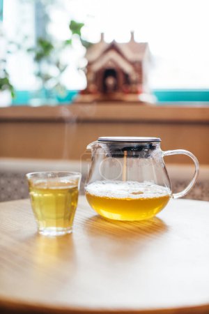 Téléchargez les photos : Gros plan de thé chaud dans une théière en verre sur une table dans un café. - en image libre de droit