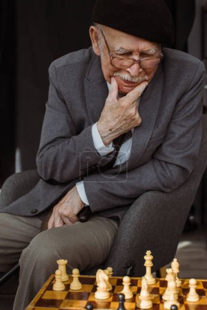 Foto de Hombre mayor pensando en su próximo movimiento en una partida de ajedrez. - Imagen libre de derechos