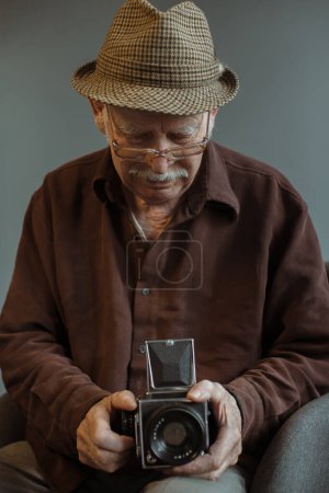 Téléchargez les photos : Un vieux photographe avec un appareil photo moyen format dans les mains. - en image libre de droit
