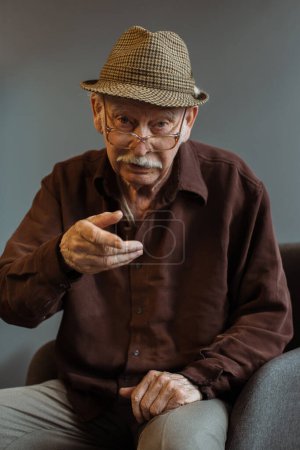 Foto de Un anciano con gestos de gafas durante una conversación con un interlocutor. - Imagen libre de derechos