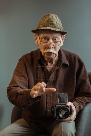Foto de Un viejo fotógrafo con una cámara de cine de formato medio en sus manos. - Imagen libre de derechos