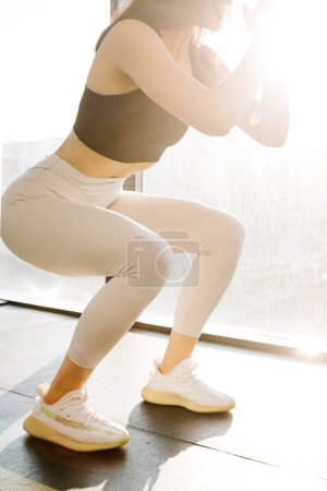 Téléchargez les photos : Close up. Athletic girl in sportswear, white leggings and black top doing squats in the gym. - en image libre de droit