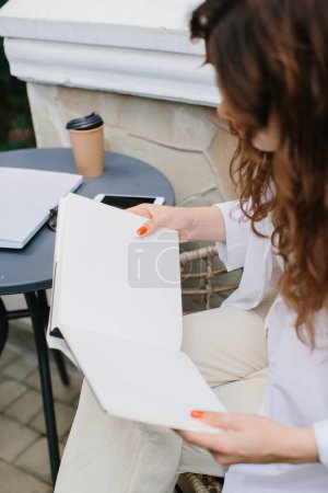 Foto de Libro de revistas de imágenes burlonas. La chica en la mesa de la cafetería leyendo la revista. - Imagen libre de derechos