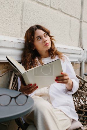 Foto de Libro de revistas de imágenes burlonas. La chica en la mesa de la cafetería leyendo la revista. - Imagen libre de derechos