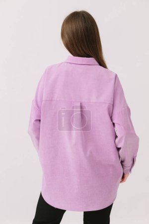 Téléchargez les photos : Photo d'une belle femme brune dans une chemise violette colorée isolée sur un fond blanc. Modèle de chemise. - en image libre de droit