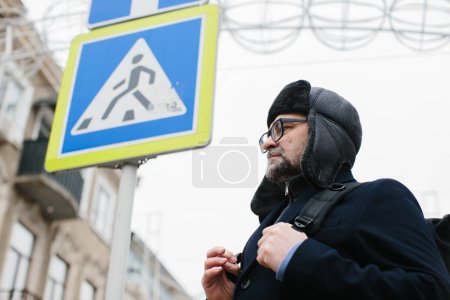Téléchargez les photos : Homme âgé profitant d'une promenade dans la ville d'hiver le week-end. Le concept de vie urbaine et de loisirs. - en image libre de droit