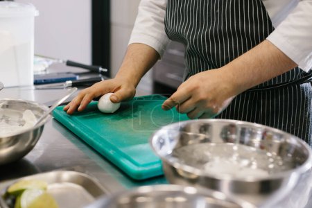 Foto de De cerca. Un cocinero macho está limpiando huevos cocidos en la cocina de un restaurante. - Imagen libre de derechos