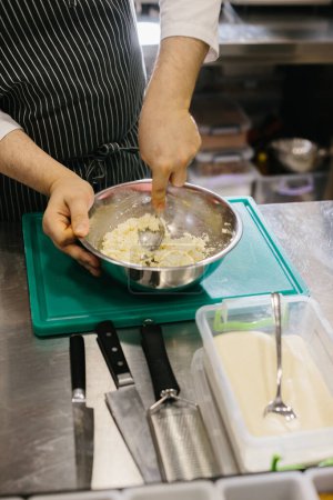Foto de De cerca. Un cocinero prepara la masa de panqueques en un tazón de metal en la cocina de un restaurante. - Imagen libre de derechos