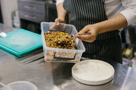 Foto de El proceso de hacer muesli en un restaurante, un chef masculino está trabajando en la cocina. - Imagen libre de derechos