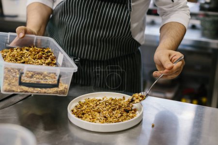 Foto de El proceso de hacer muesli en un restaurante, un chef masculino está trabajando en la cocina. - Imagen libre de derechos