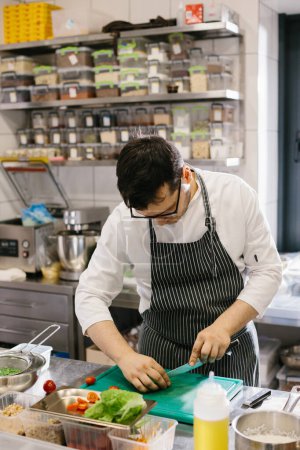 Téléchargez les photos : Préparation de légumes pour un délicieux bol : un chef masculin dans une cuisine de restaurant contemporaine. - en image libre de droit