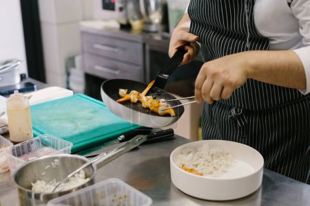 Téléchargez les photos : Préparer un bol de fruits de mer, un chef masculin prépare un délicieux plat dans une cuisine de restaurant. - en image libre de droit