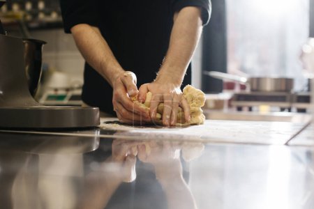Téléchargez les photos : Ferme là. Le cuisinier pétrit la pâte avec ses mains, faisant des macarons ou des gâteaux. - en image libre de droit