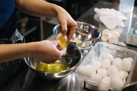 Photo for Close up. A cook in the kitchen of a cafe or bakery. Female hands break eggs for dough. - Royalty Free Image