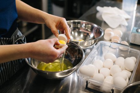Téléchargez les photos : Ferme là. Un cuisinier dans la cuisine d'un café ou d'une boulangerie. Les mains féminines cassent les œufs pour la pâte. - en image libre de droit