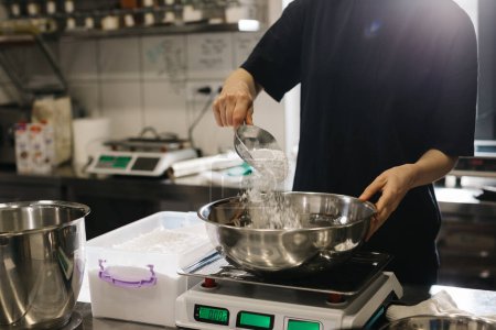 Foto de Una cocinera trabaja en una cocina industrial moderna. El proceso de hacer pasteles en una panadería o cafetería. - Imagen libre de derechos