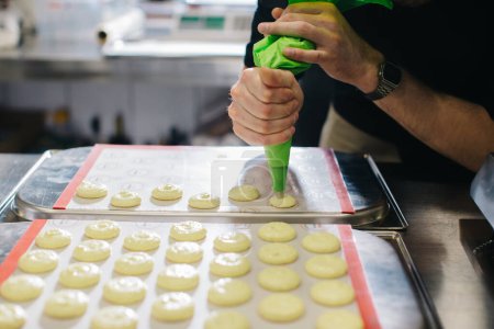 Téléchargez les photos : Un pâtissier fait des macarons dans une pâtisserie. - en image libre de droit