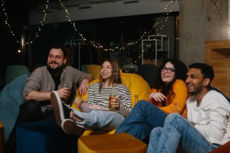 Téléchargez les photos : Une compagnie d'amis dans la soirée dans un café passer du temps ensemble regarder leur série TV préférée. - en image libre de droit