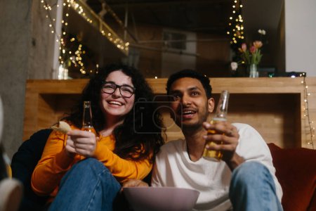 Téléchargez les photos : Une compagnie d'amis dans la soirée dans un café passer du temps ensemble regarder leur série TV préférée. - en image libre de droit