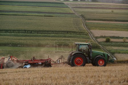 Foto de Un tractor arada un campo de trigo. El concepto del trabajo de un agricultor y la cosecha. - Imagen libre de derechos