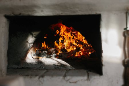 Photo for Ukrainian traditional oven in the house. Firewood is burning in the oven, preparation for baking bread. - Royalty Free Image