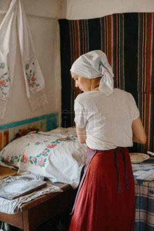 Photo for Ukrainian traditional village house. A woman prepares dough for baking bread. - Royalty Free Image
