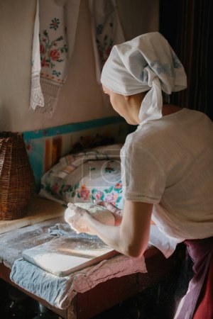 Photo for A woman in traditional Ukrainian clothing kneads bread dough. - Royalty Free Image