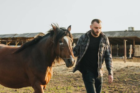 Téléchargez les photos : Un jeune agriculteur travaille avec des chevaux à la ferme. - en image libre de droit